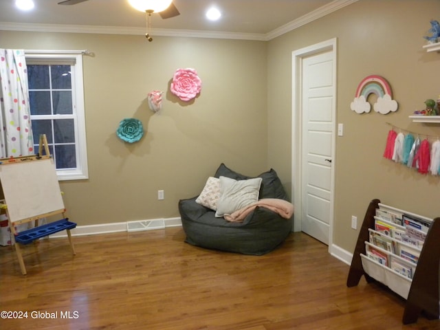 living area featuring wood-type flooring, ceiling fan, and crown molding