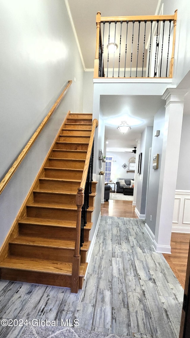 staircase with hardwood / wood-style floors and ornamental molding