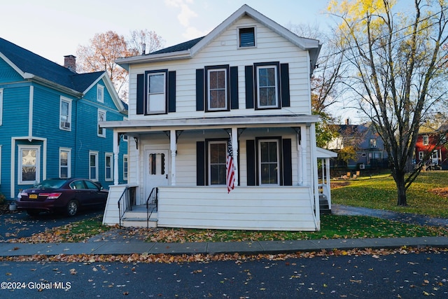 front facade with covered porch and a front yard