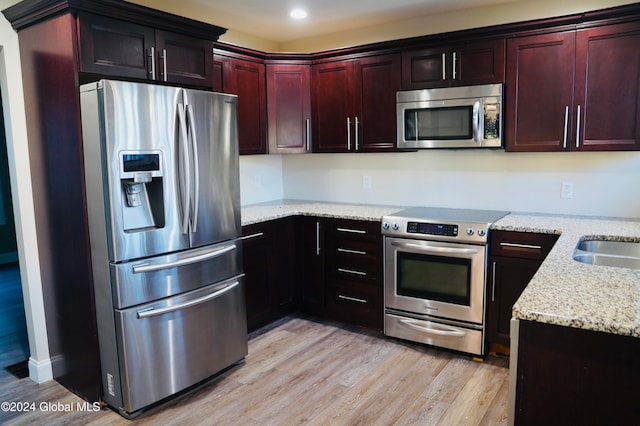 kitchen featuring stainless steel appliances, light stone countertops, and light hardwood / wood-style floors