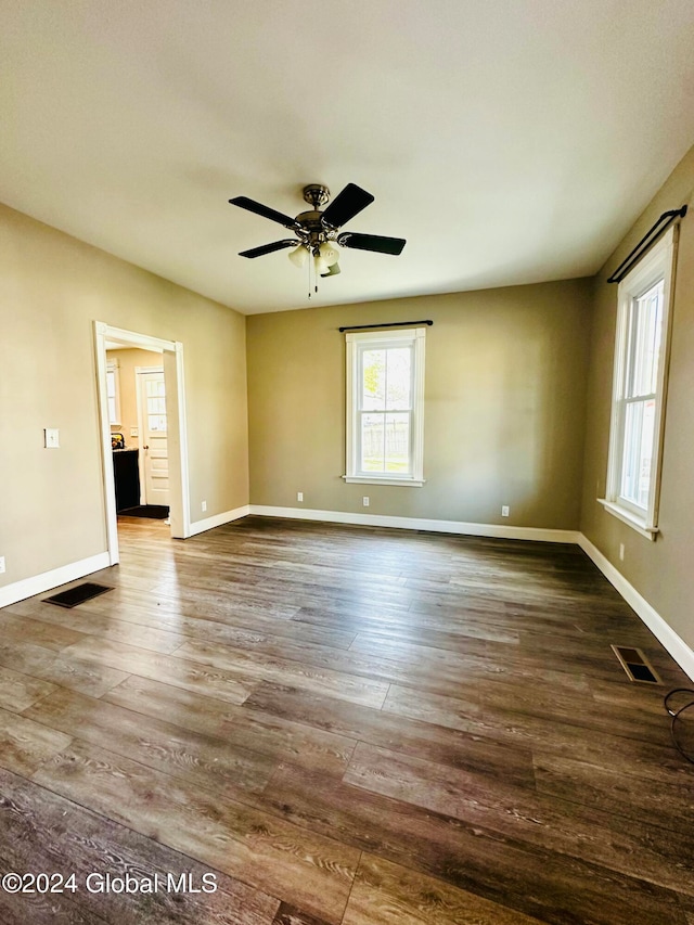 empty room with ceiling fan and dark hardwood / wood-style floors