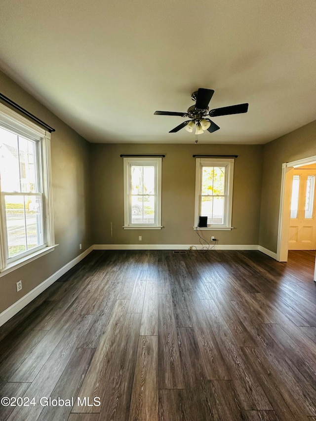 spare room with dark hardwood / wood-style flooring, a wealth of natural light, and ceiling fan