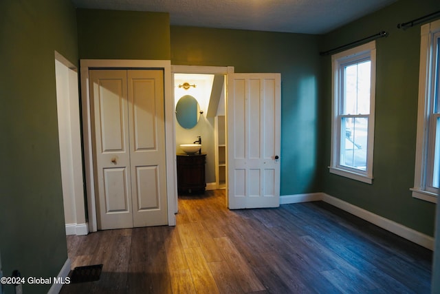 unfurnished bedroom with ensuite bathroom, hardwood / wood-style floors, a textured ceiling, and sink