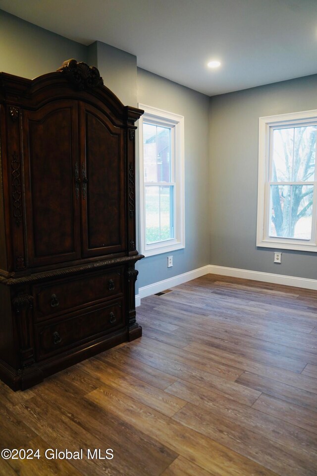 unfurnished bedroom with hardwood / wood-style floors and multiple windows