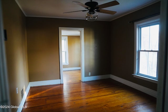 empty room featuring dark wood-type flooring, ceiling fan, and crown molding