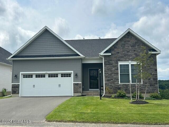 craftsman inspired home with a garage and a front lawn