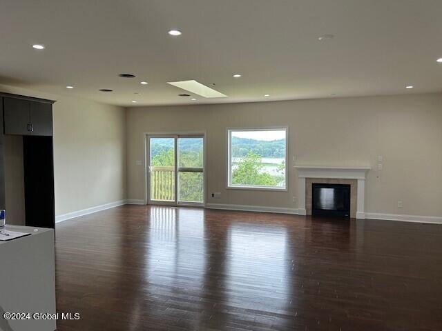 unfurnished living room with a skylight and dark hardwood / wood-style floors