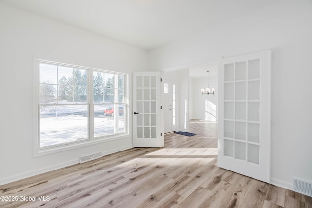 empty room featuring light hardwood / wood-style flooring and a notable chandelier