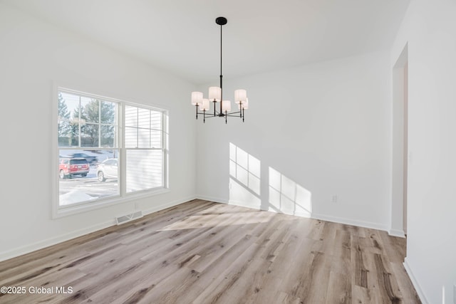 unfurnished dining area featuring a chandelier and light hardwood / wood-style floors