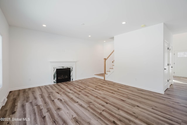 unfurnished living room with a premium fireplace and light hardwood / wood-style floors