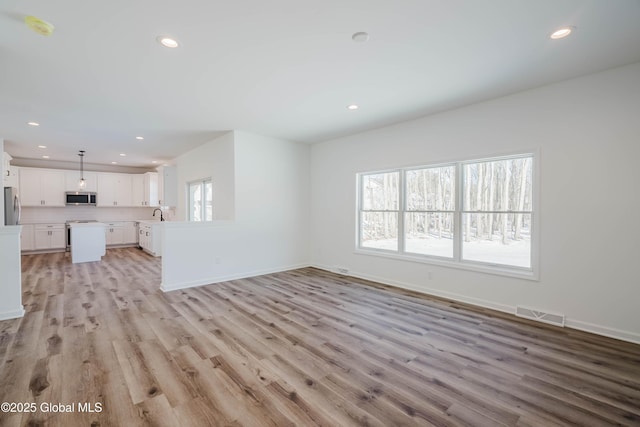 unfurnished living room featuring sink and light hardwood / wood-style floors