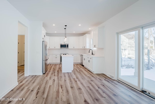 kitchen with pendant lighting, white cabinetry, stainless steel appliances, and a kitchen island