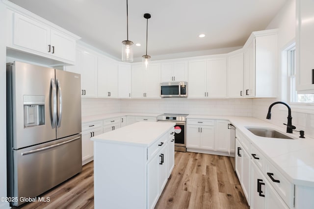 kitchen with stainless steel appliances, a kitchen island, sink, and white cabinets