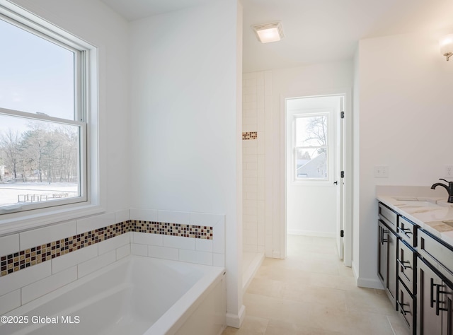 bathroom with vanity, a wealth of natural light, and a tub to relax in