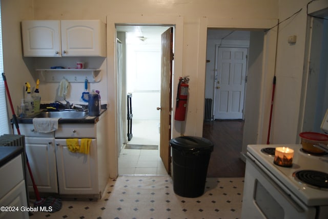 kitchen with white cabinetry, sink, and white electric range oven