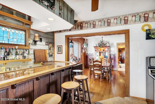 bar with ceiling fan and light hardwood / wood-style floors