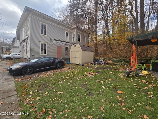 rear view of house with a storage unit and a yard