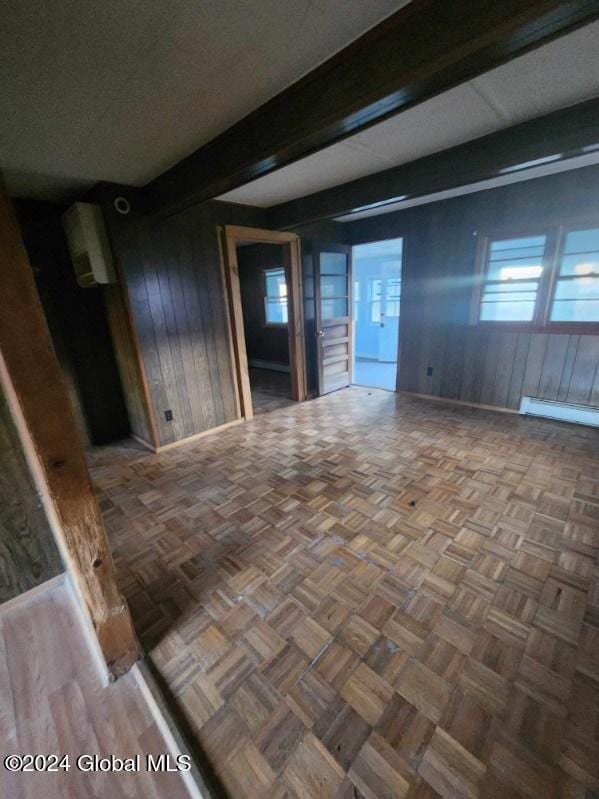 spare room with wood walls, parquet floors, and a baseboard heating unit