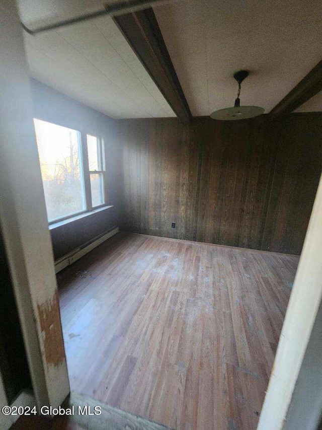 empty room featuring wooden walls, hardwood / wood-style floors, and baseboard heating