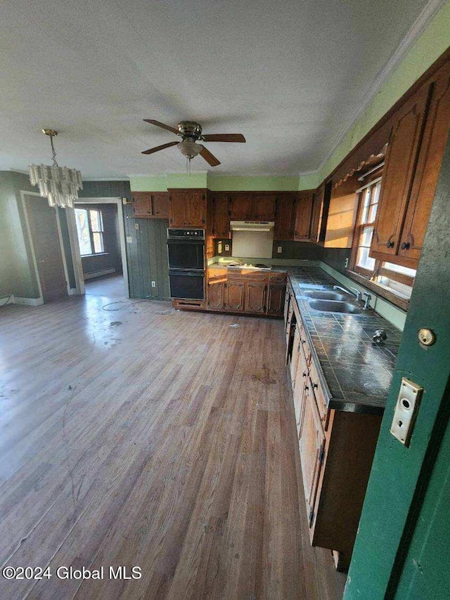 kitchen with ceiling fan with notable chandelier, dark wood-type flooring, a textured ceiling, sink, and double oven