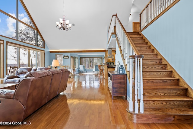 living room with a chandelier, light hardwood / wood-style flooring, high vaulted ceiling, and a healthy amount of sunlight