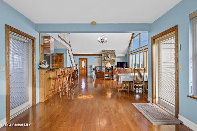 interior space featuring a stone fireplace, wood-type flooring, and an inviting chandelier