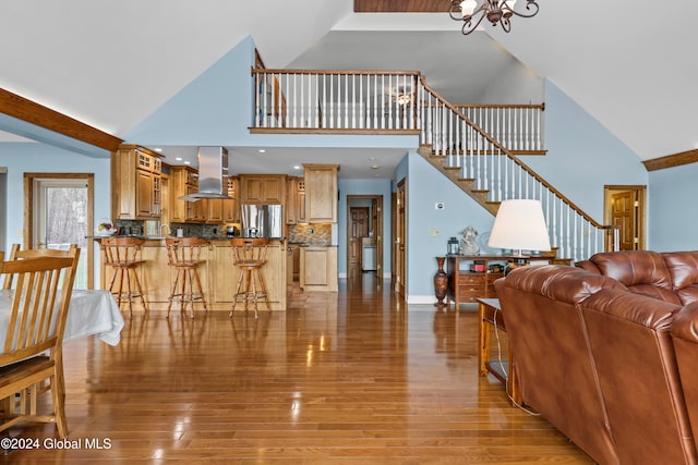 living room featuring a chandelier, light hardwood / wood-style flooring, and high vaulted ceiling