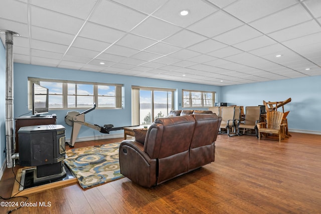 living room featuring a wood stove, hardwood / wood-style floors, and a drop ceiling