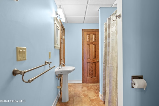 bathroom featuring a drop ceiling, curtained shower, and sink