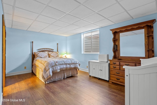 bedroom featuring a drop ceiling and wood-type flooring