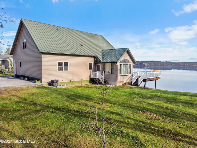 back of house with a water view and a yard