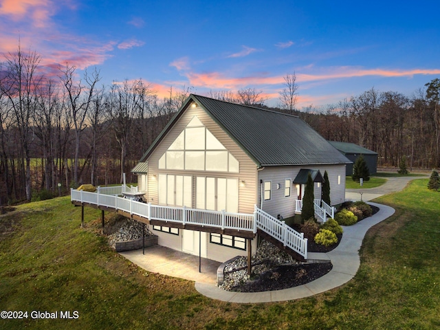 back house at dusk featuring a lawn