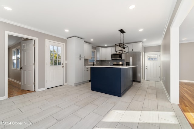 kitchen with white cabinetry, a kitchen island, appliances with stainless steel finishes, decorative light fixtures, and light wood-type flooring