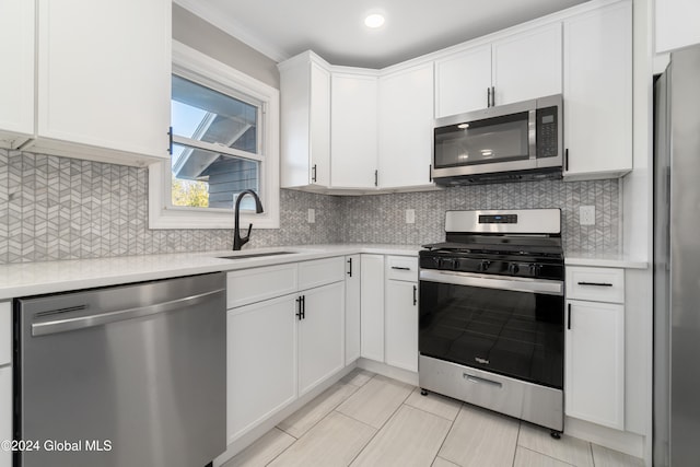 kitchen with appliances with stainless steel finishes, tasteful backsplash, sink, light tile patterned floors, and white cabinets