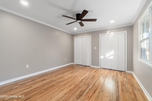 unfurnished bedroom with two closets, ornamental molding, ceiling fan, and light hardwood / wood-style floors