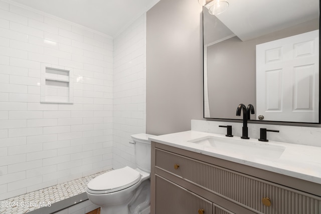 bathroom with vanity, ornamental molding, toilet, and tiled shower