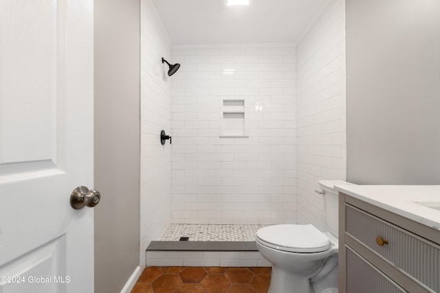 bathroom with tile patterned floors, tiled shower, toilet, vanity, and ornamental molding