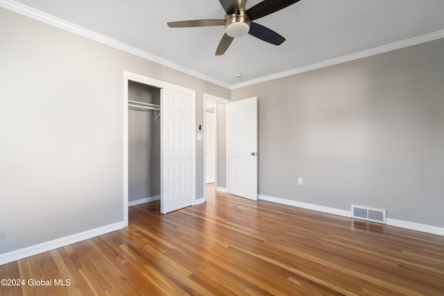 unfurnished bedroom with a closet, hardwood / wood-style floors, ornamental molding, and ceiling fan