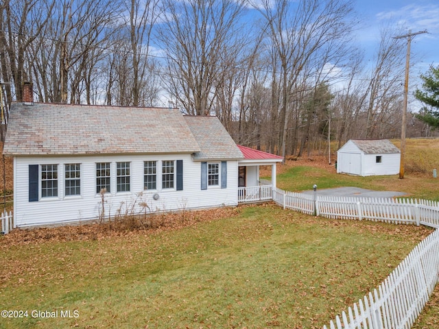 view of front of house with a front yard, a porch, and a shed