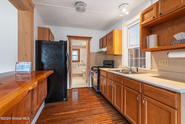 kitchen with black refrigerator, gas stove, a wealth of natural light, and dark wood-type flooring