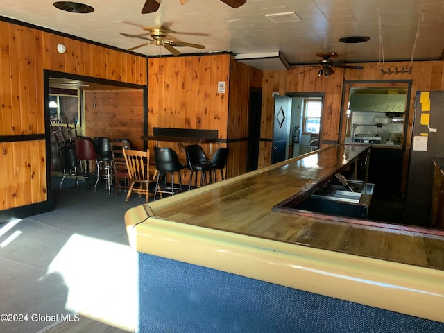 kitchen with wood walls, ceiling fan, and dark carpet