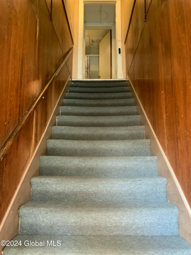 stairway with concrete floors and wood walls