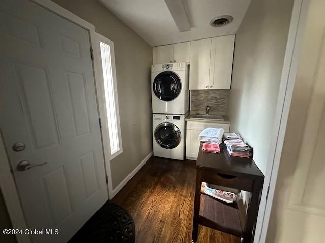 clothes washing area featuring sink, dark hardwood / wood-style flooring, cabinets, and stacked washer and dryer