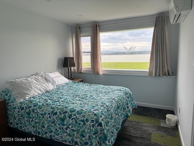 bedroom with a water view, multiple windows, and a wall mounted AC