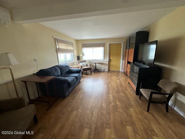 living room with a wall mounted air conditioner and dark hardwood / wood-style floors