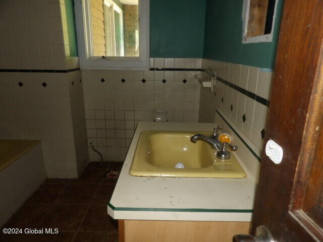 bathroom with tile patterned flooring, tile walls, and sink