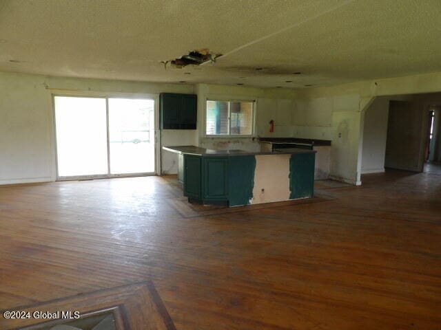 kitchen with wood-type flooring, white cabinets, a textured ceiling, and a kitchen island