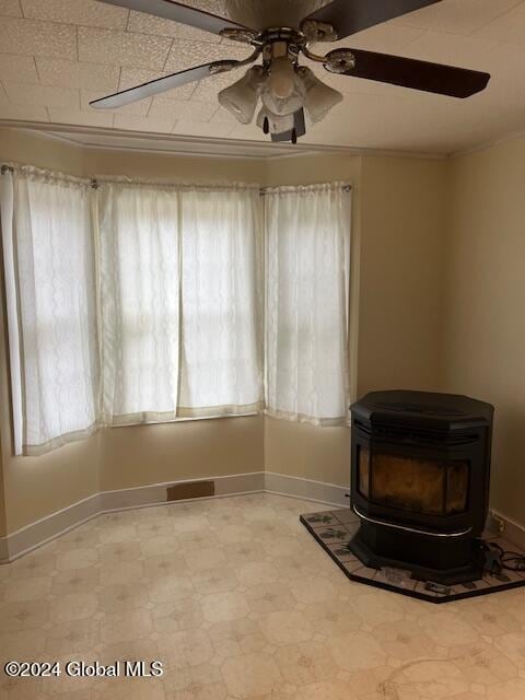 interior space featuring ceiling fan and a wood stove