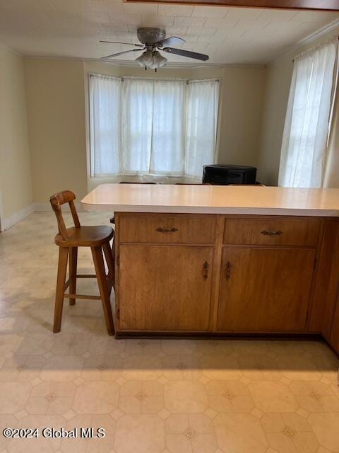 kitchen with ceiling fan, kitchen peninsula, a breakfast bar area, and light tile patterned floors