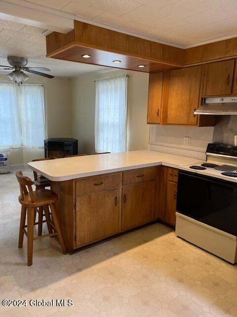 kitchen with ceiling fan, kitchen peninsula, white range with electric cooktop, crown molding, and a breakfast bar